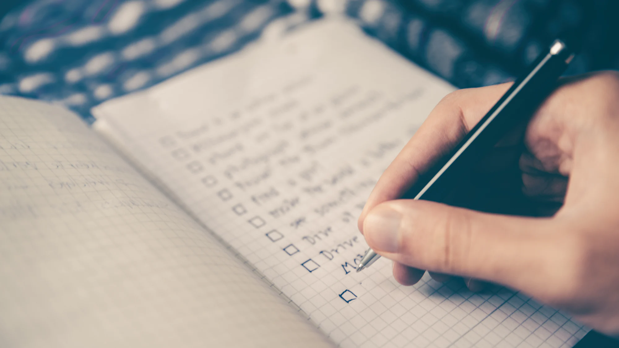 A hand writing a checklist in a notebook