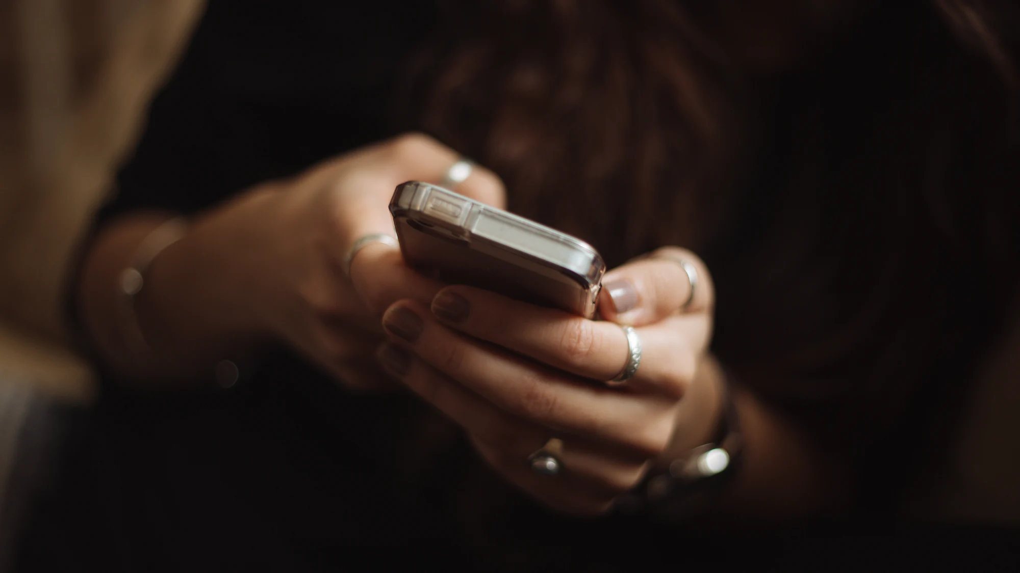 Hands holding a smartphone in warm, low light