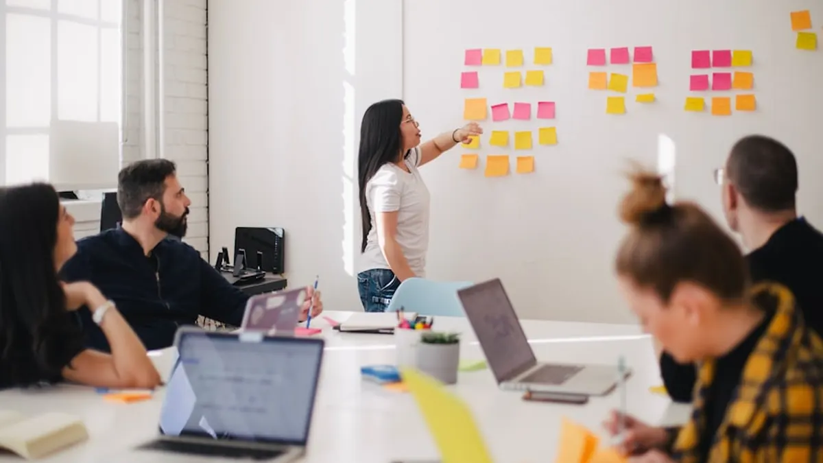 A team standing at a whiteboard covered in coloured sticky notes
