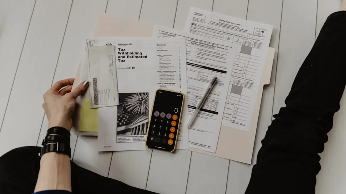 Printed tax documents and a calculator on a white desk