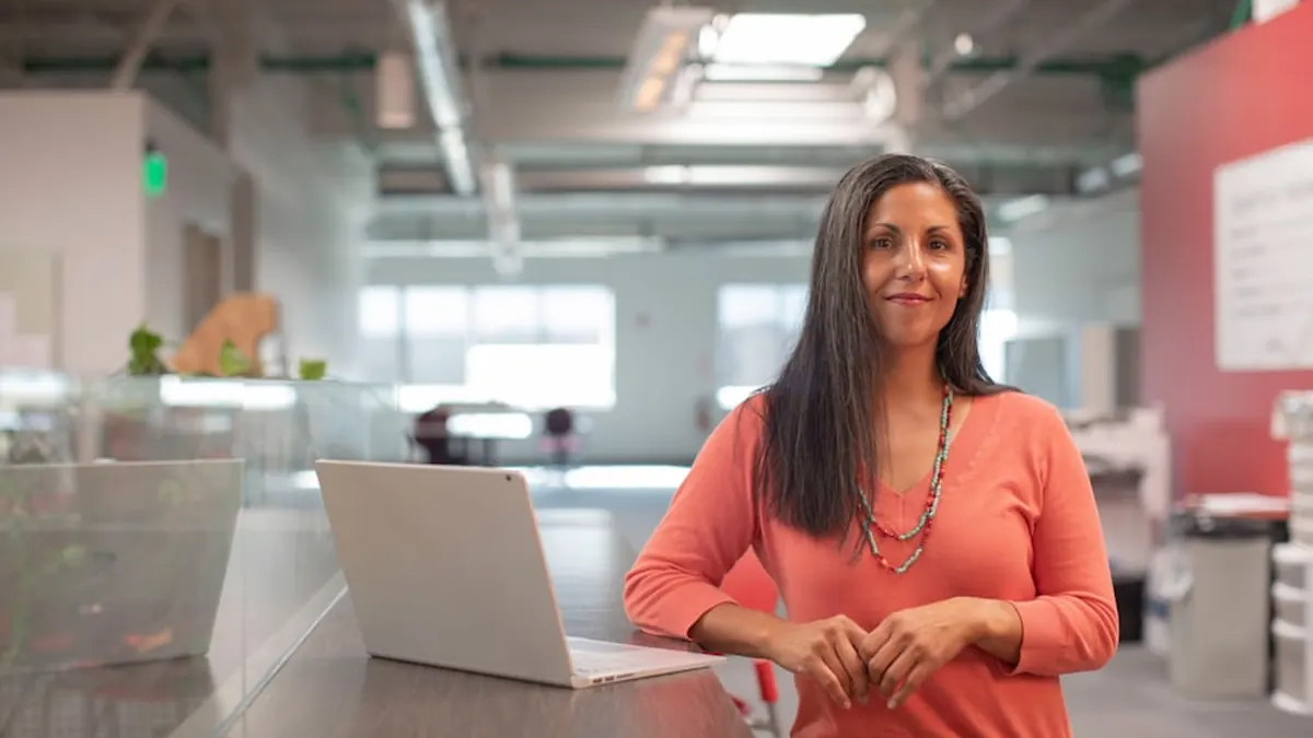 A woman working at a laptop in a bright open plan office