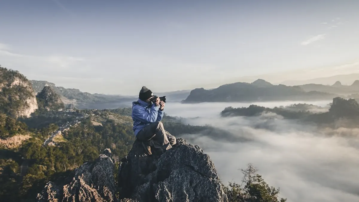A photographer with a camera standing above a valley at sunrise