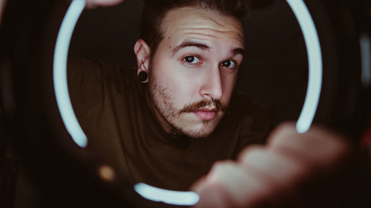 A young man looking straight into the camera through the circle of a ring light