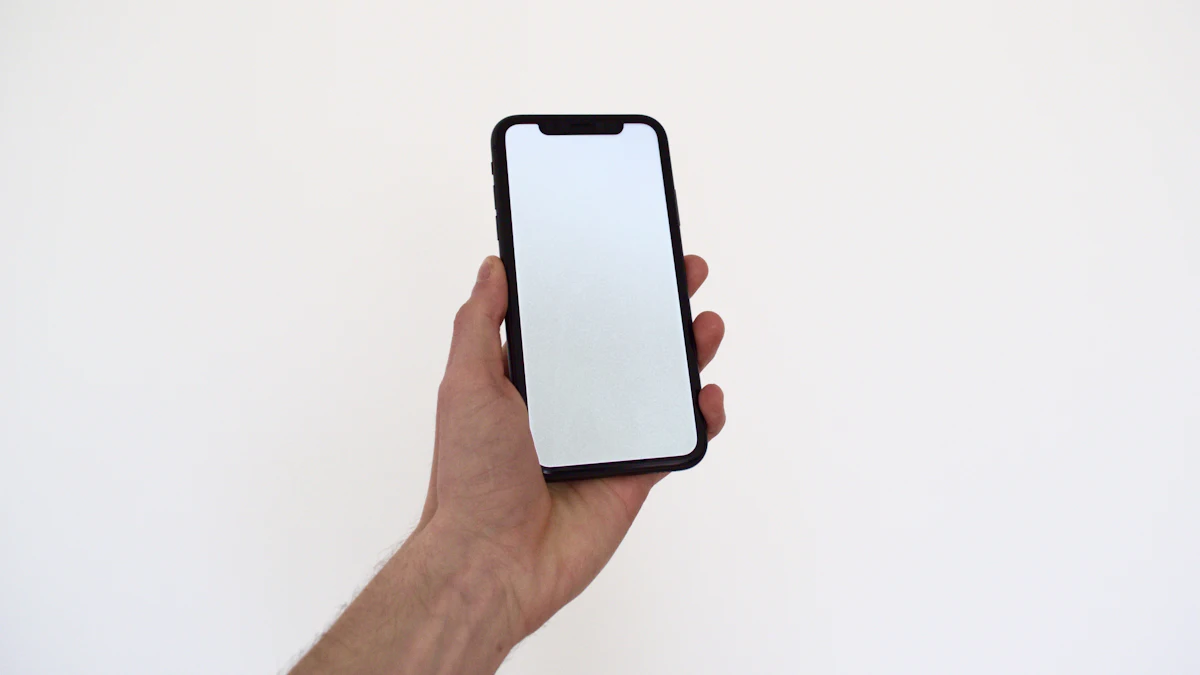 A hand holding up a smartphone with a blank white screen against a pale wall