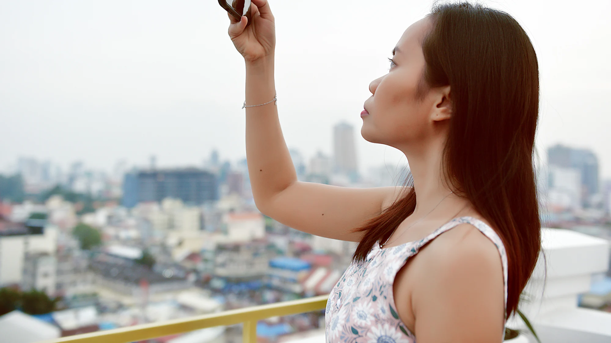 A woman taking a selfie with a city skyline behind her