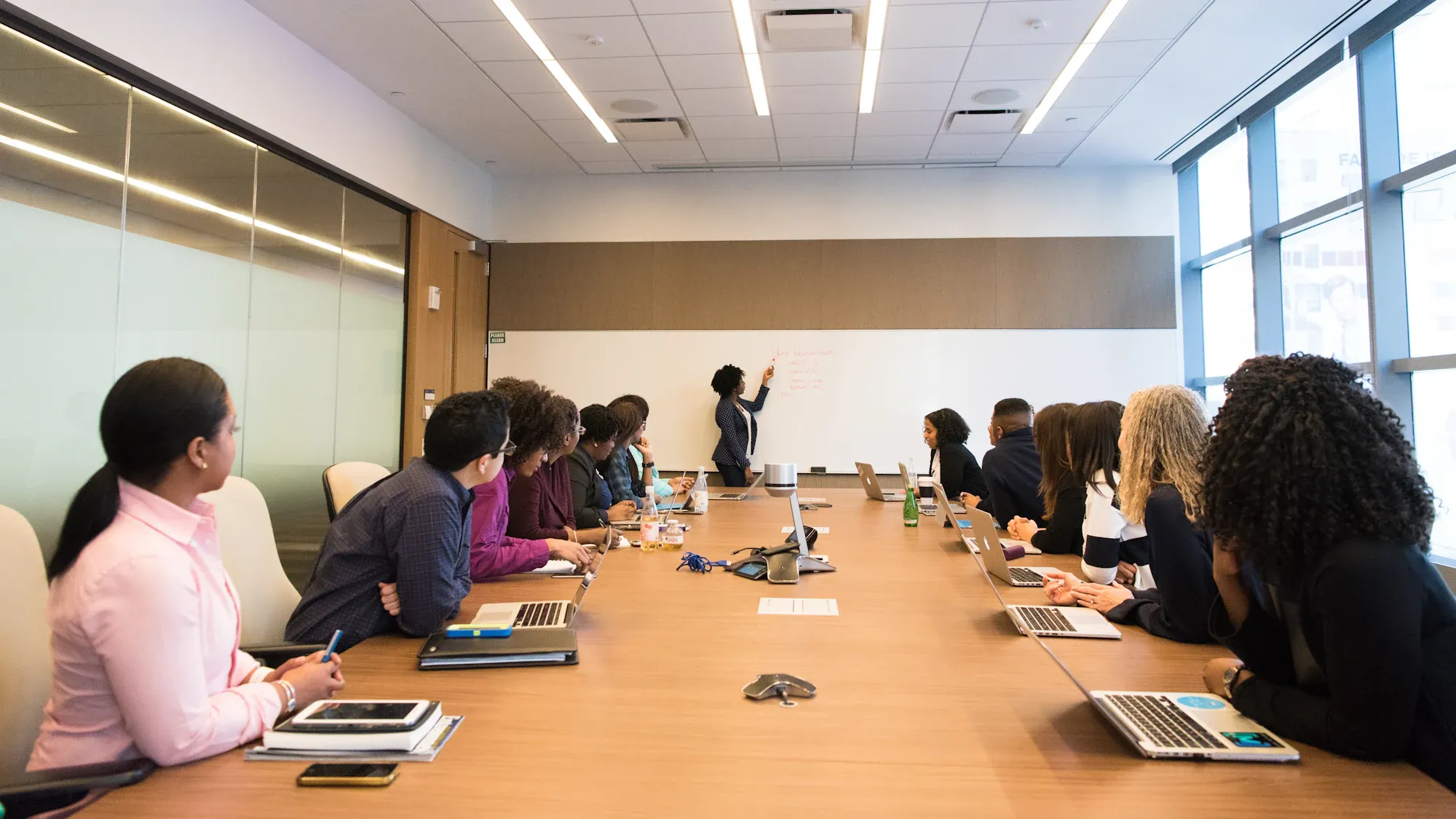 A team around a conference table listening to a woman present