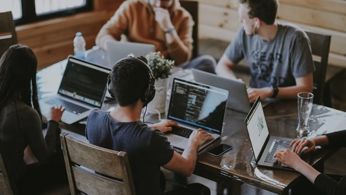 A team working on laptops around a shared table in a co-working space
