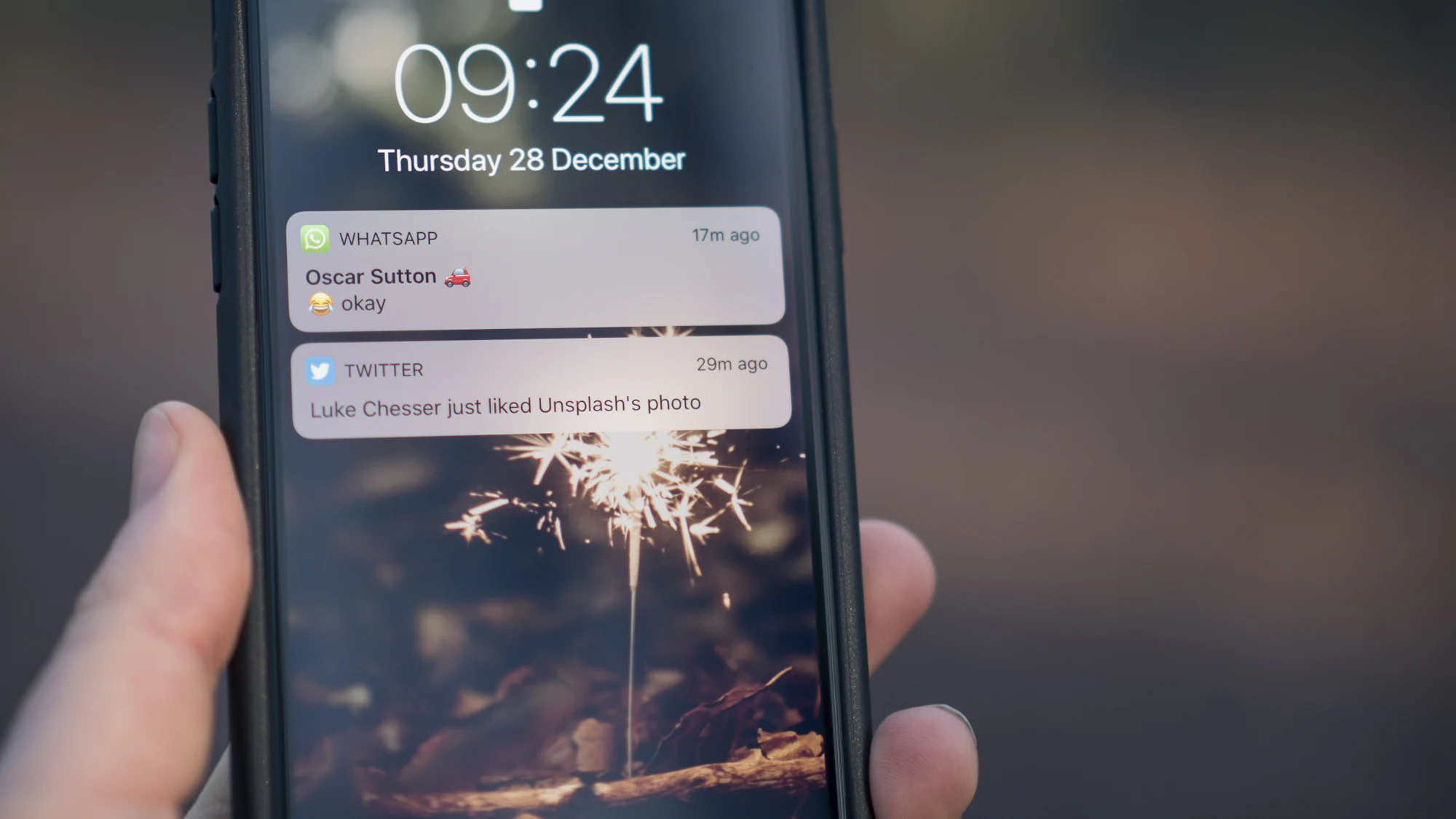 A hand holding a phone with notifications on the lock screen